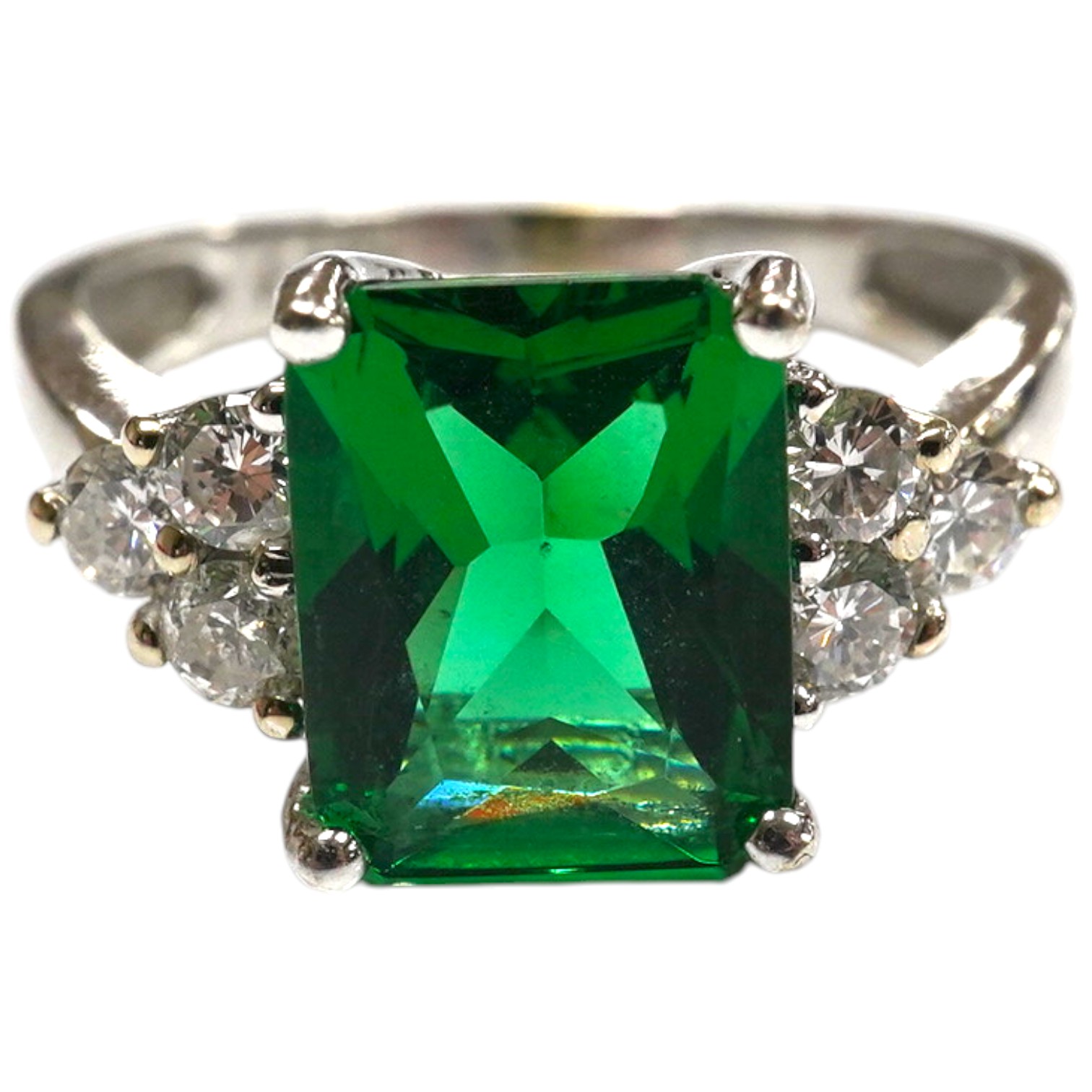 A modern 14k white metal and single stone green paste set dress ring, with six stone diamond set shoulders, size O, gross weight 3.6 grams. Condition - fair